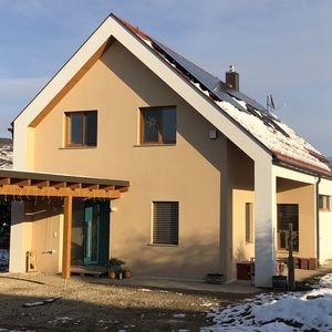 Einfamilienhaus mit heller Fassade und rotem Dach, im Rohbauzustand.