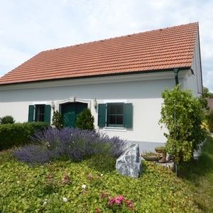 Weißes Wohnhaus mit Garten und rotem Dach, klassische ländliche Bauweise.