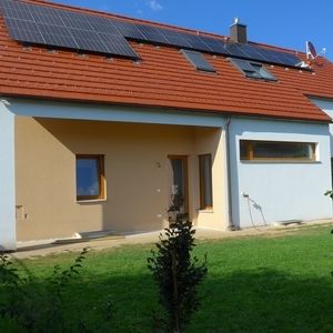 Einfamilienhaus mit orangefarbener Fassade und rotem Satteldach, Neubau mit Garage.