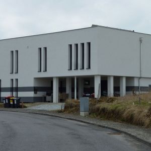 Neubau mit Flachdach und heller, strukturierter Fassade, moderne Architektur.