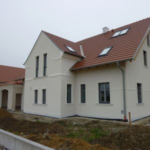 Klassisches Einfamilienhaus mit Satteldach und heller Putzfassade, teilweise im Rohbau.