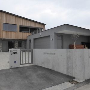Flachdachhaus mit grauem Sichtbeton und Carport, moderner Stil.