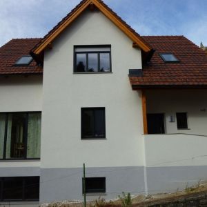 Modernes Haus mit dunklen Fensterrahmen und heller Fassade, rechteckige Bauform.
