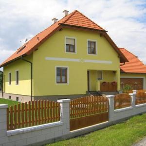 Zweigeschossiges Einfamilienhaus mit gelber Fassade, Satteldach und dekorativem Holzzaun im Vorgarten