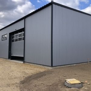 Gewerbehalle mit grauer Blechfassade und großem Rolltor