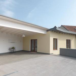 Überdachte Terrasse mit hellem Fliesenboden am Neubau