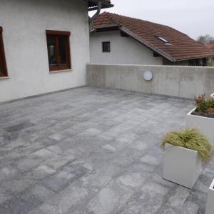 Terrasse mit grauer Natursteinplatte vor weißem Haus