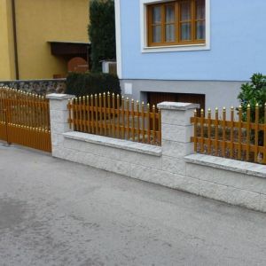 Weißer Zaun mit geschwungenen Pfeilern und Gartenbereich