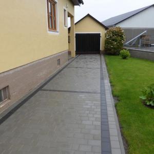 Schmale Einfahrt mit grauen Betonpflastersteinen