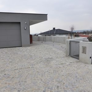 Zufahrt mit Pflastersteinen vor modernem Flachdachhaus