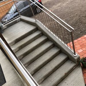 Schmale Betontreppe mit Edelstahlgeländer