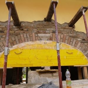 Baustelle mit historischem Mauerbogen, gestützt von einem gelben Stahlträger