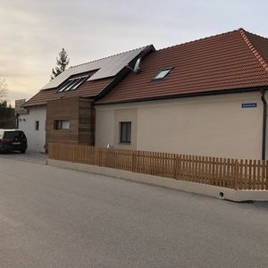 Straßenszene mit modernisiertem Einfamilienhaus mit weißer Fassade und Ziegeldach