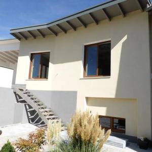 Modernes Wohnhaus mit hellem Putz, Flachdach, Außentreppe und bepflanztem Vorgarten
