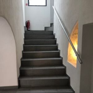 Innenaufnahme eines schmalen Treppenaufgangs mit schwarzer Stiege und weißem Wandanstrich