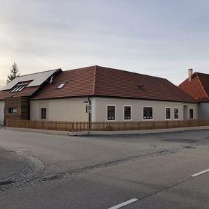 Langes Gebäude mit rotem Ziegeldach und weißer Fassade entlang einer Straßenkurve