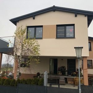 Zweigeschossiges Wohnhaus mit hellgelber Fassade und dunklen Fensterrahmen