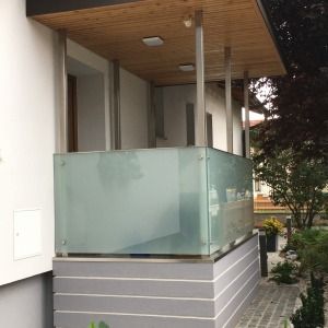 Moderner Balkon mit Glasgeländer an einem Haus mit hellem Holzvordach