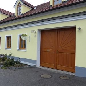 Gelbes Wohnhaus mit weißem Sockel, großen Holztoren und kleinen Fenstern