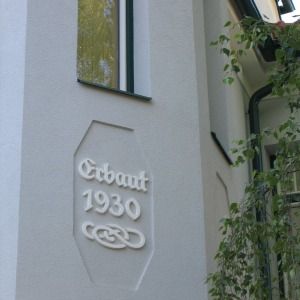 Nahaufnahme einer weißen Hauswand mit der Prägung Erbaut 1930