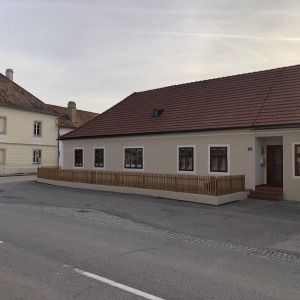 Langgestrecktes, einstöckiges Gebäude mit beigem Anstrich und rotem Dach, an einer Straße gelegen