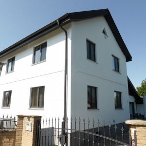 Weißes Wohnhaus mit Satteldach, zwei Etagen und schlichten schwarzen Fensterrahmen