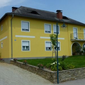 Gelbes Haus mit zwei Etagen, dunkelgrünem Dach und gemauertem Rundbogen-Eingang