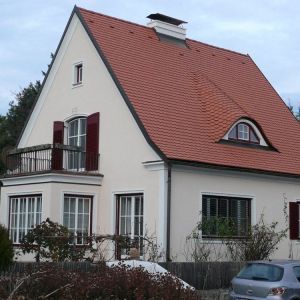 Einfamilienhaus mit rotem Satteldach, heller Fassade und Sprossenfenstern