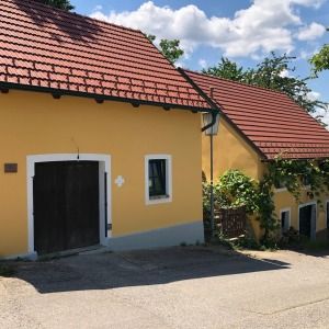 Wohnhaus mit gelber Fassade und rotem Ziegeldach, schwarzes Holztor im Eingangsbereich, traditionelle Bauweise