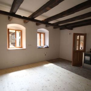 Innenraum mit Holzdecke und freiliegenden Balken, drei Rundbogenfenster mit Holzrahmen und hellem Boden