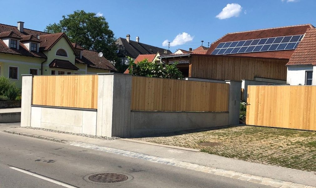 Moderner Sichtbetonzaun mit Holzelementen an der Straße