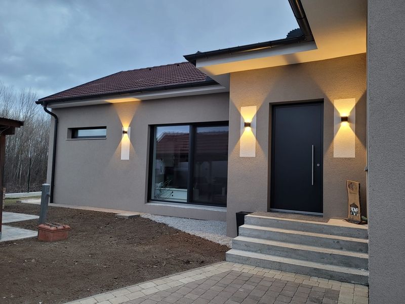 Moderne Küche mit weißer Arbeitsplatte, Spüle und Herd, beleuchtet von Tageslicht durch ein Fenster